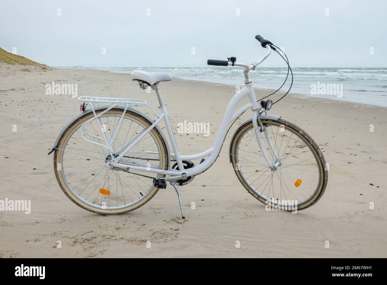Bici bianca sulla sabbia vicino al Mar Baltico. Bicicletta sulla spiaggia sabbiosa, nessuno. Foto Stock