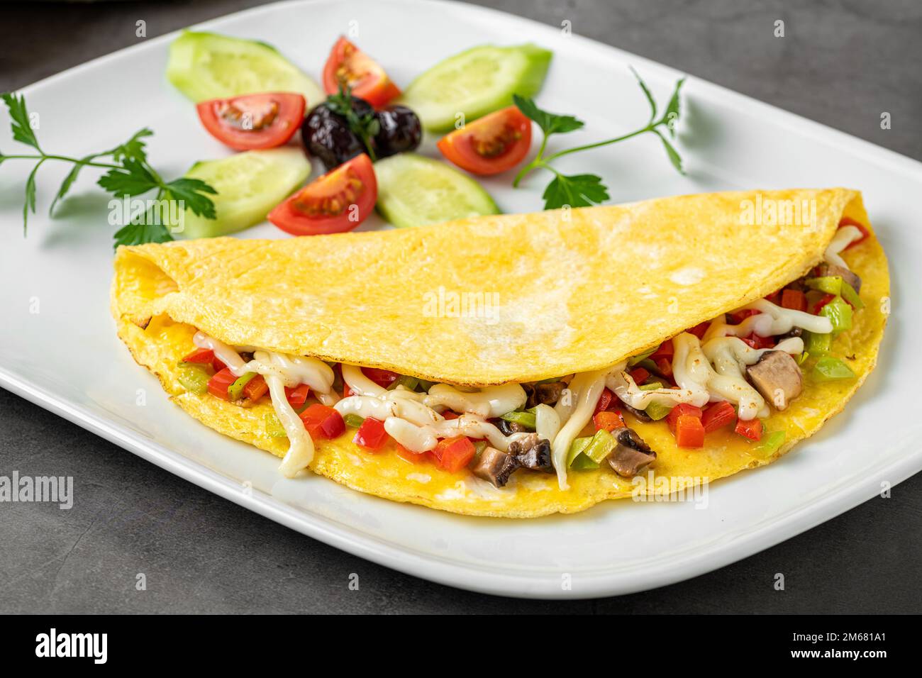 Omelette con formaggio, funghi e verdure su un piatto di porcellana bianca Foto Stock