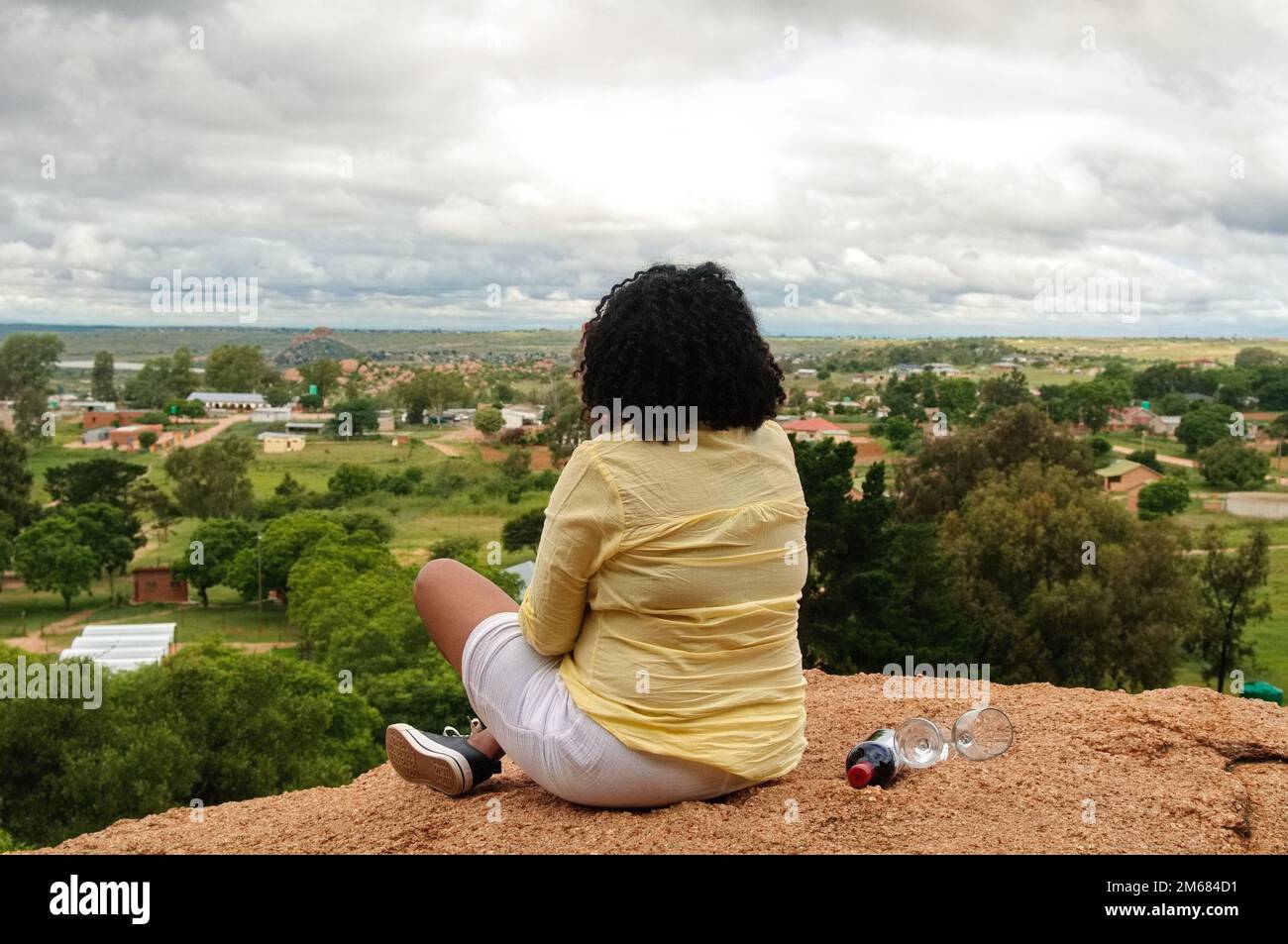 Una donna si rilassa su una roccia gigante in un pomeriggio coperto in un tranquillo villaggio africano Foto Stock Una donna si rilassa su una roccia gigante in un pomeriggio coperto in un tranquillo villaggio africano Foto Stock