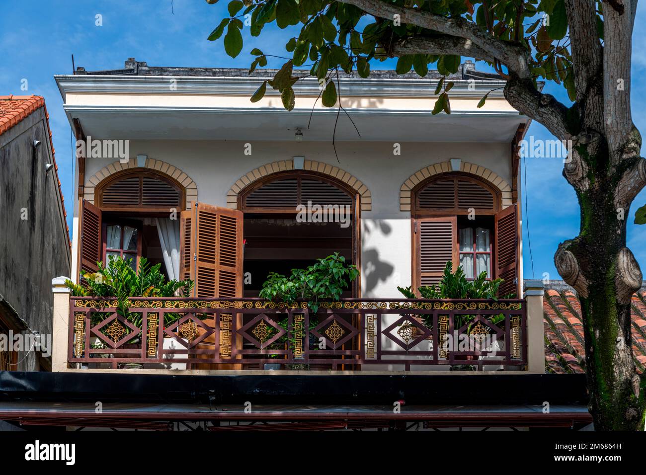 L'influenza francese nell'architettura in Vietnam è molto evidente con le persiane, le finestre e il balcone di questo edificio a Hoi An. Foto Stock