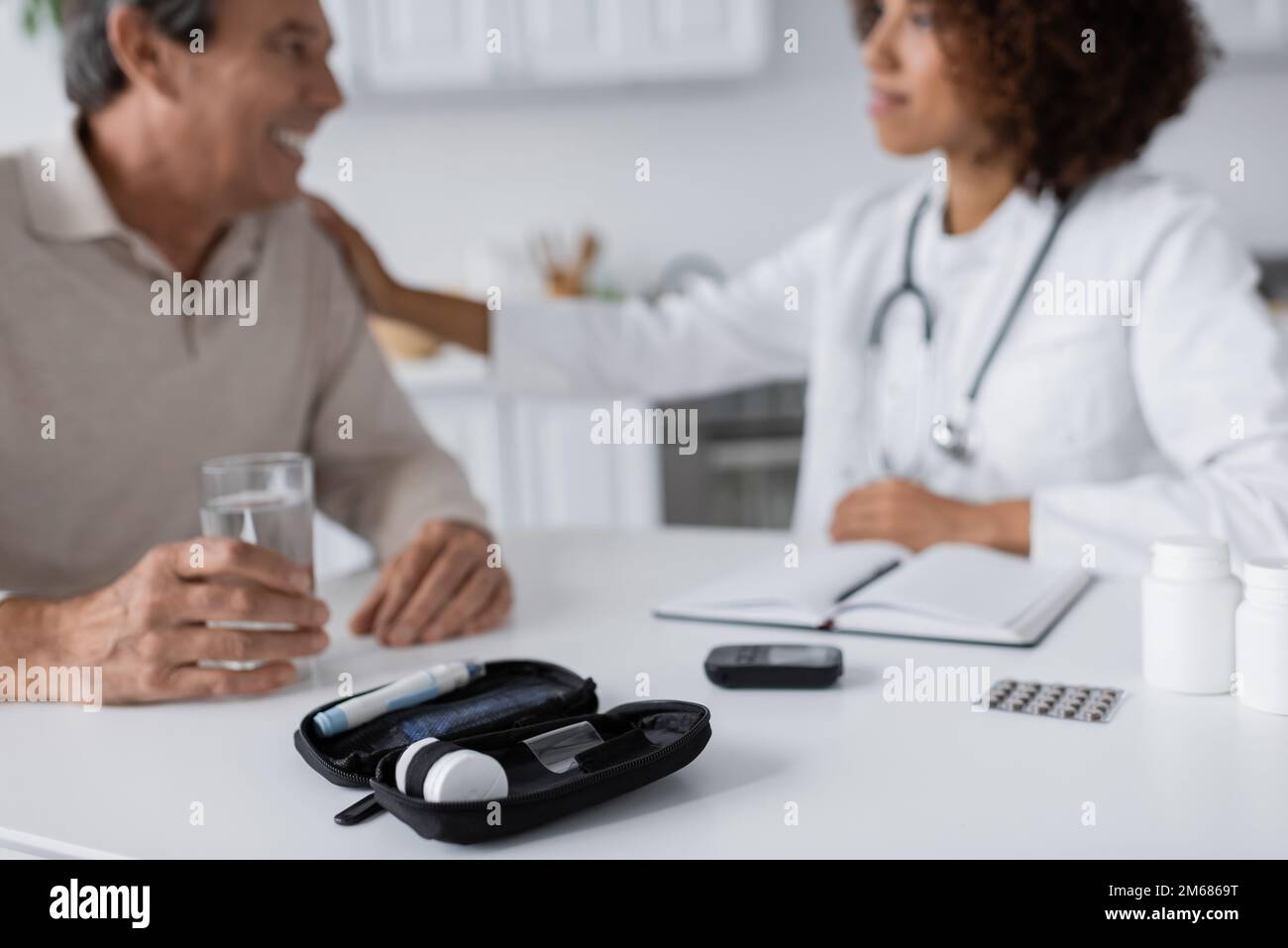 glucometro e penna lancetta vicino a un medico afro-americano e a un uomo di mezza età con diabete su sfondo sfocato, immagine di scorta Foto Stock