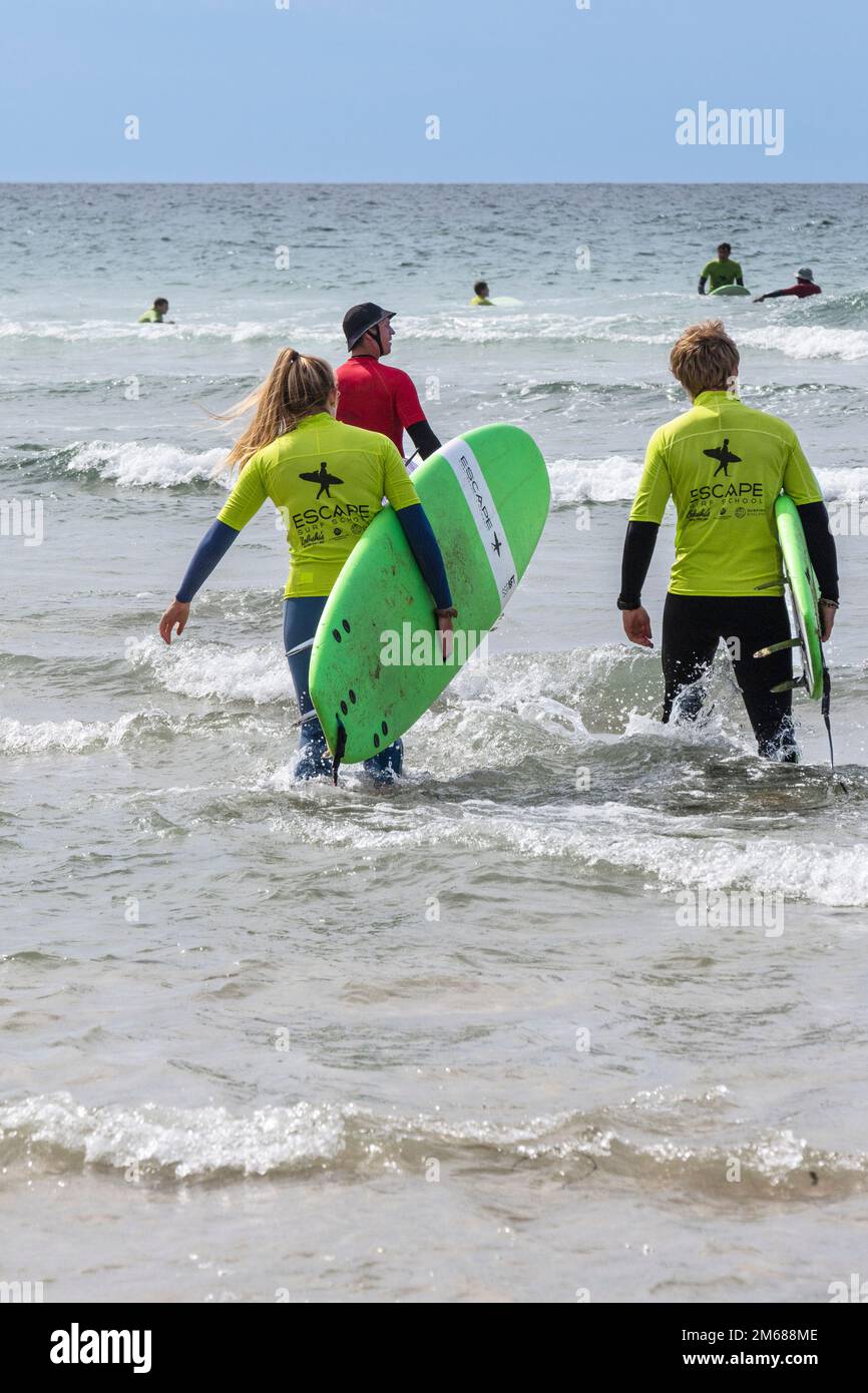 I vacanzieri che prendono parte a una lezione di surf con un istruttore a Fistral Beach a Newquay in Cornovaglia nel Regno Unito. Foto Stock