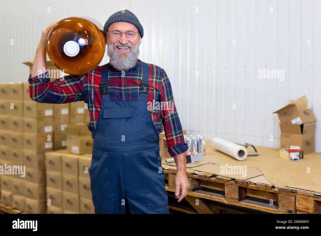 Caricatore sorridente e soddisfatto in piedi nel magazzino della fabbrica Foto Stock