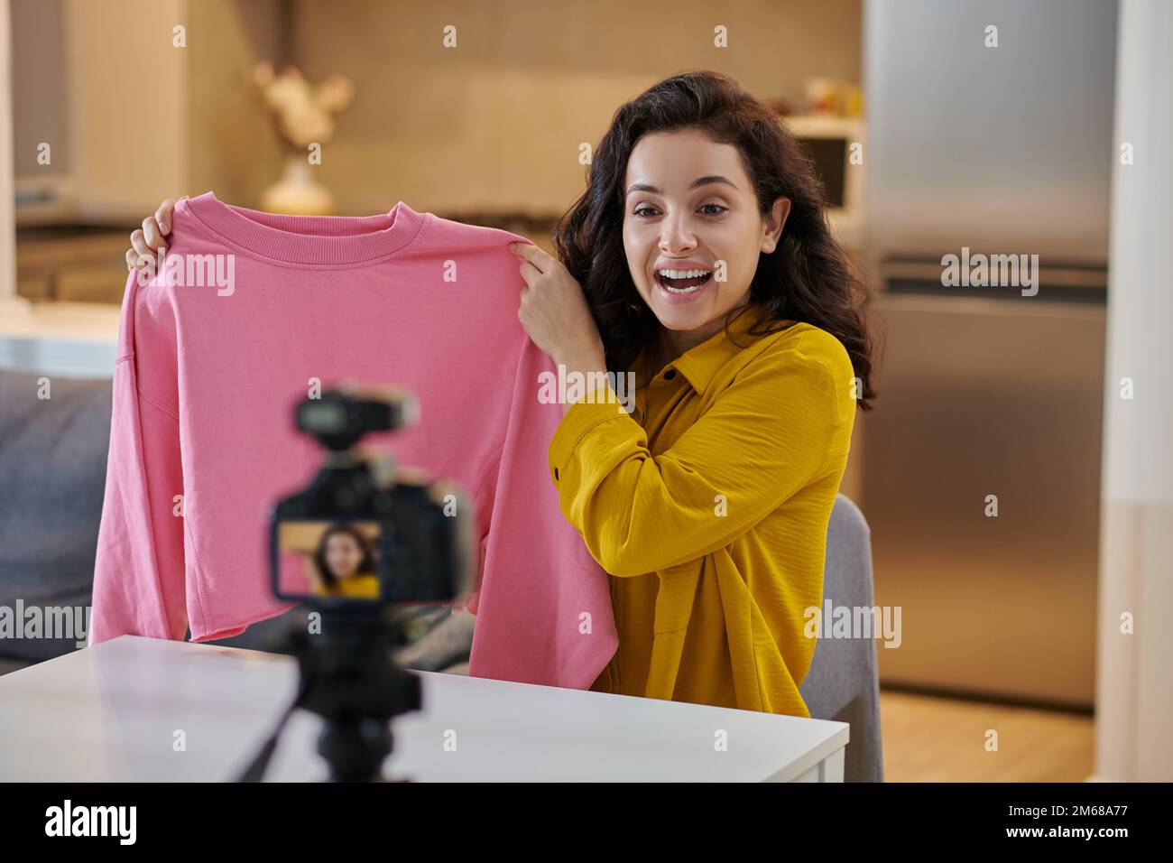 Giovane donna dai capelli scuri che mostra una blusa rosa online Foto Stock