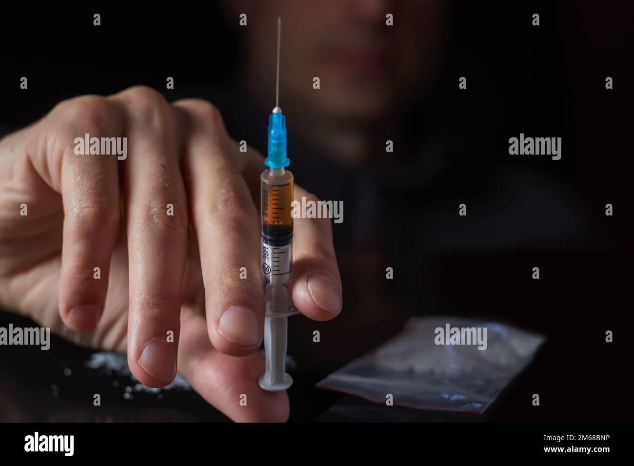 Siringa del farmaco in mano. Un tossicodipendente con un'altra dose del farmaco nella siringa. Guy dipendente, il concetto di anti-droga. tossicodipendente maschile. Foto Stock
