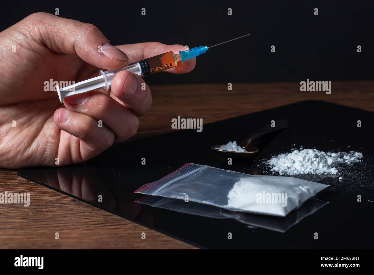 Siringa del farmaco in mano. Un tossicodipendente con un'altra dose del farmaco nella siringa. Guy dipendente, il concetto di anti-droga. tossicodipendente maschile. Foto Stock