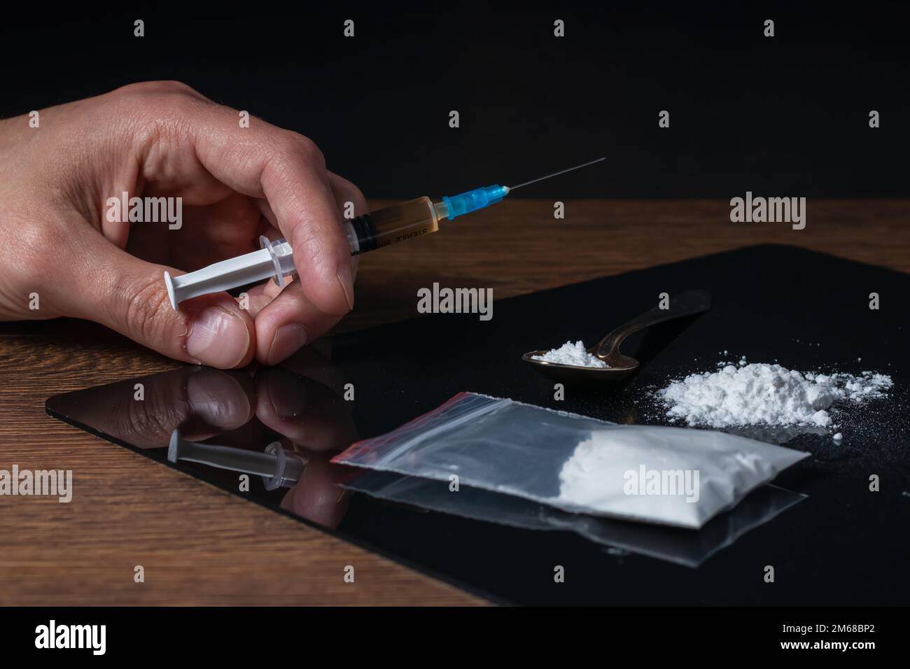 Siringa del farmaco in mano. Un tossicodipendente con un'altra dose del farmaco nella siringa. Guy dipendente, il concetto di anti-droga. tossicodipendente maschile. Foto Stock