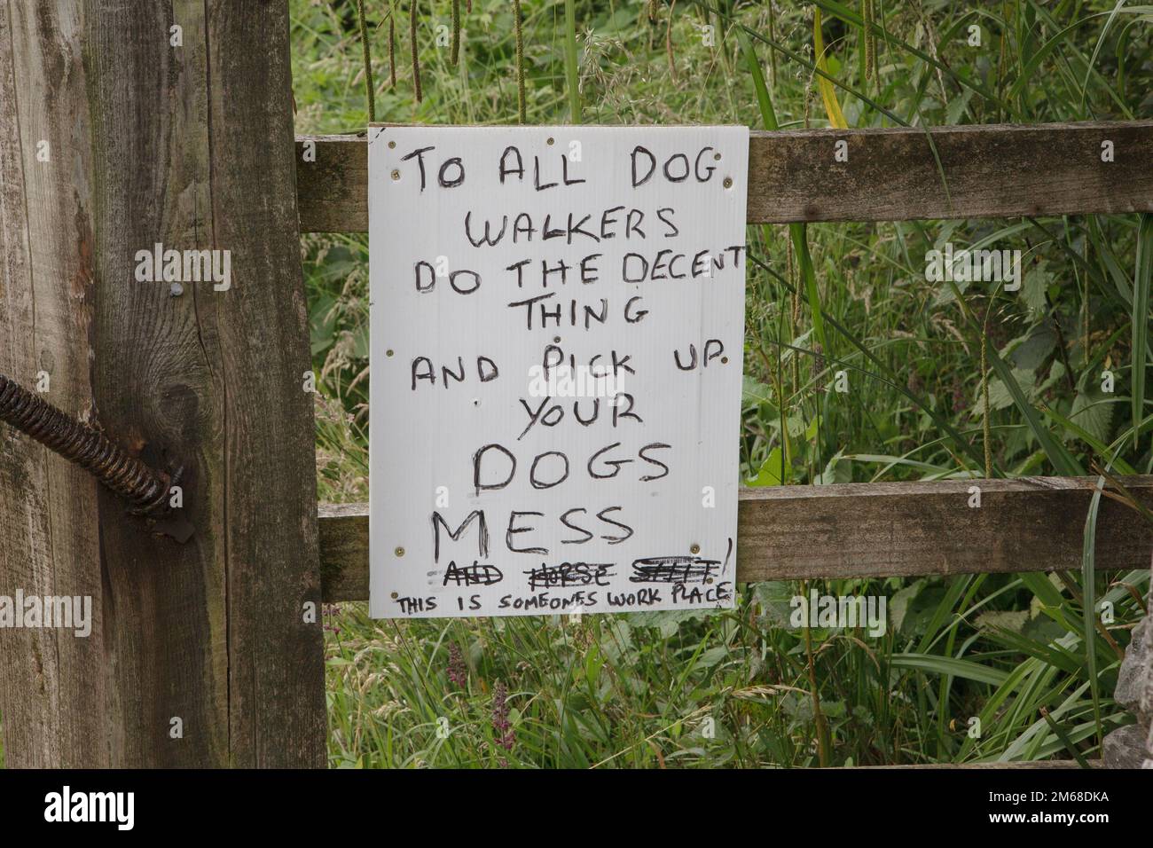 Un cartello fatto a mano sul cancello di un sentiero chiede agli escursionisti di prendere il loro pasticcio cane Foto Stock