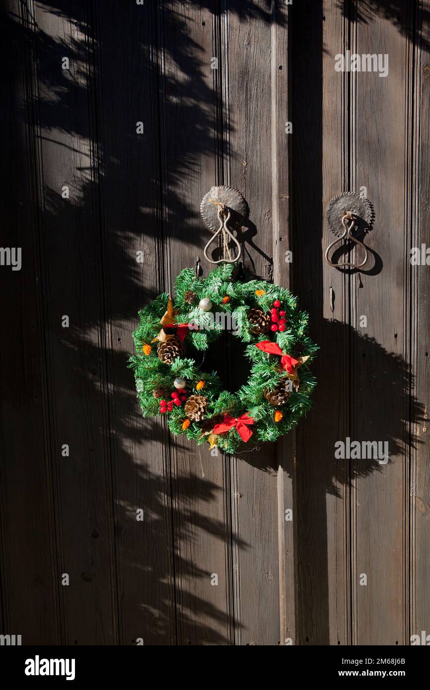 La corona della porta di Natale su una porta vintage, lunghe ombre Foto Stock