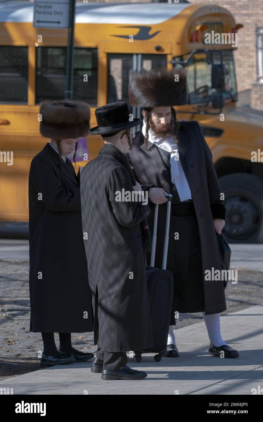 Il venerdì pomeriggio, una famiglia hassidica attende un autobus per portarli da Williamsburg a Borough Park, dove trascorreranno Shabbat. A Brooklyn, New York. Foto Stock