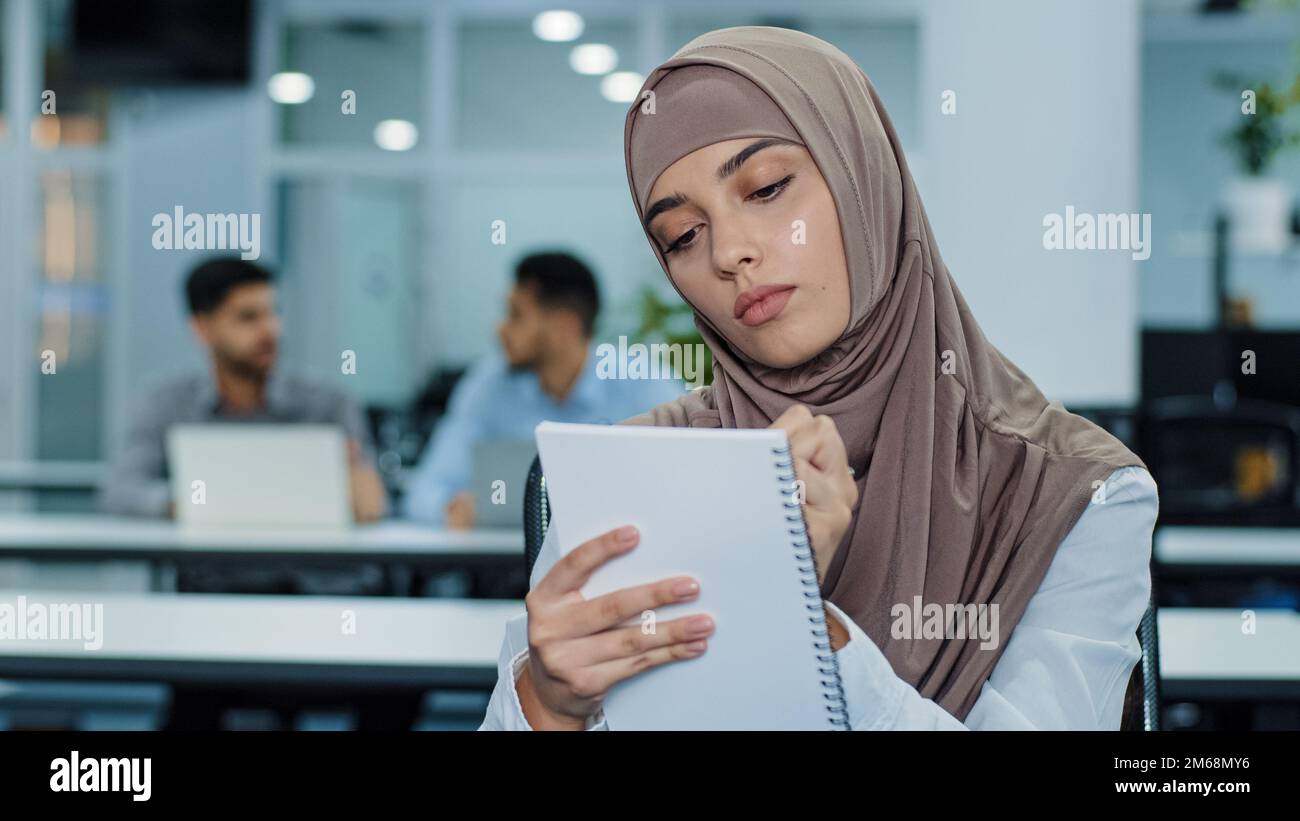 Islam uomo d'affari musulmano in hijab etnico felice di successo donna ufficio imprenditore lavoratore manager seduto in coworking scrivere appunti rapporto Foto Stock