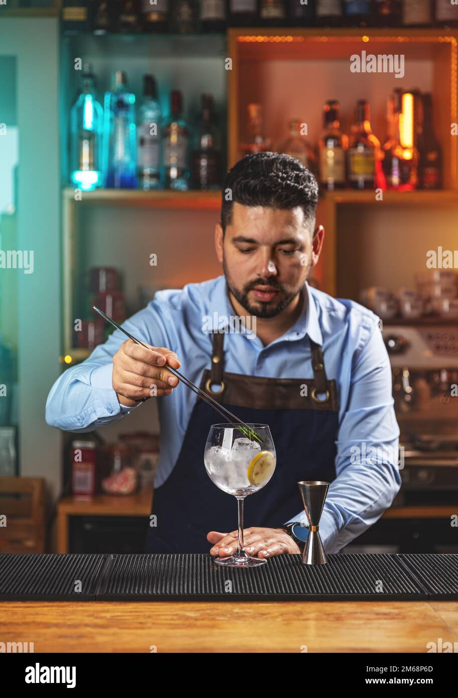 Barista che decora un bicchiere ripieno di bevanda alcolica utilizzando una fetta di limone Foto Stock