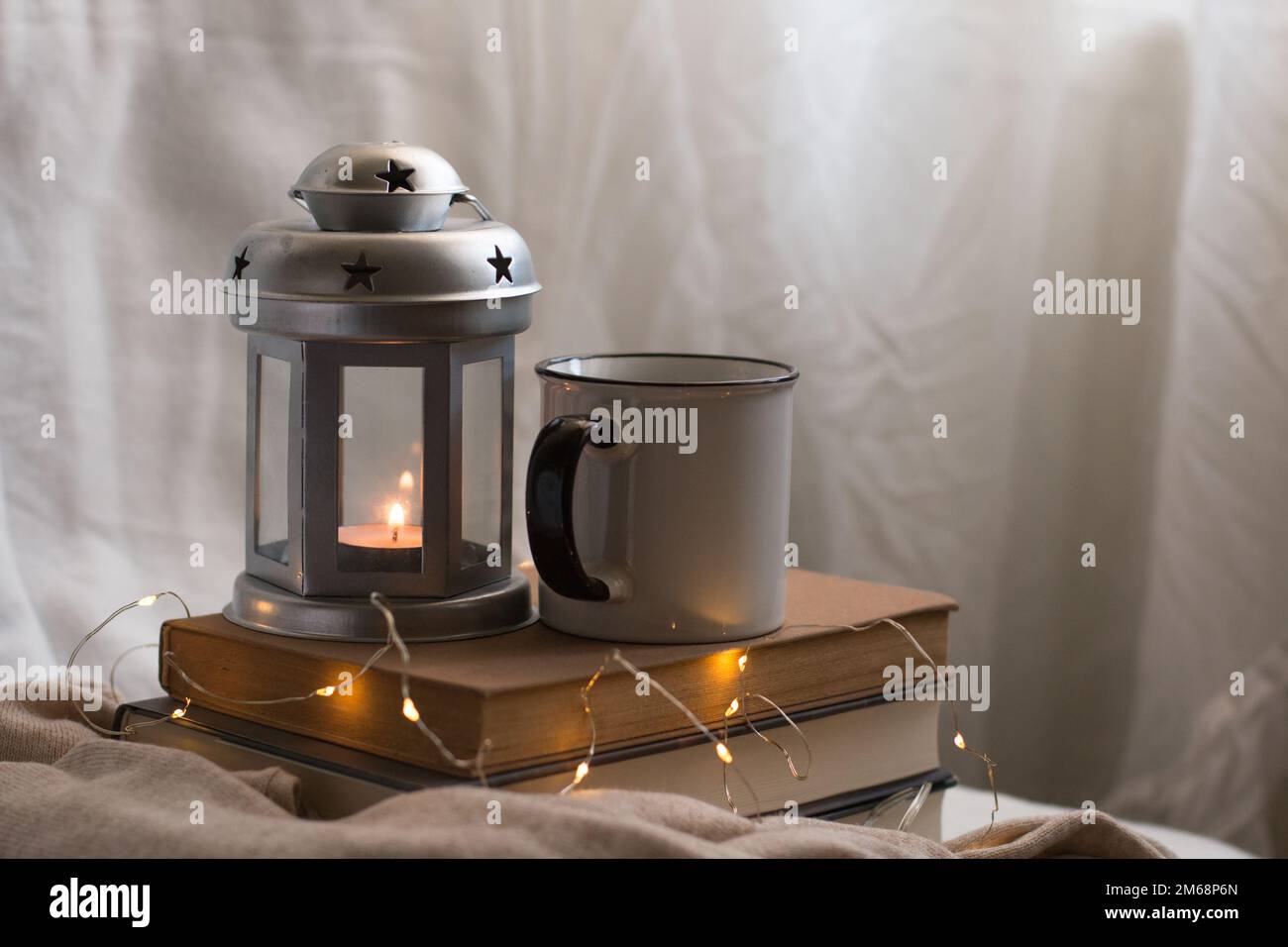 Accogliente composizione di caffè, candela e libri per le vacanze. Godere di cose semplici al coperto durante l'inverno. Foto Stock