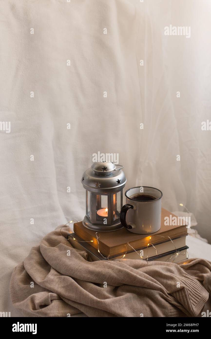Accogliente composizione di caffè, candela e libri per le vacanze. Godere di cose semplici al coperto durante l'inverno. Foto Stock