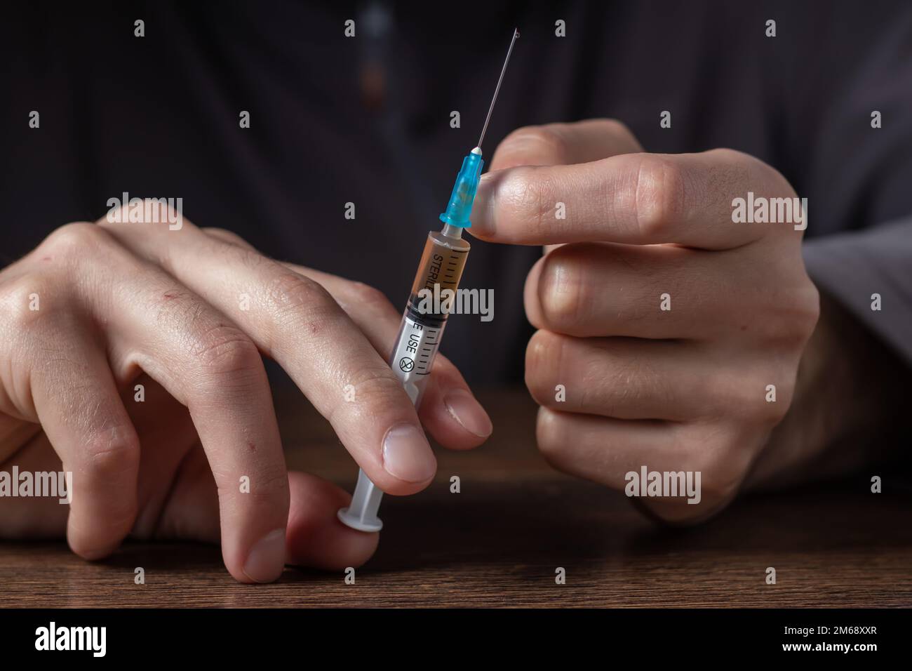 Siringa del farmaco in mano. Un tossicodipendente con un'altra dose del farmaco nella siringa. Guy dipendente, il concetto di anti-droga. tossicodipendente maschile. Foto Stock