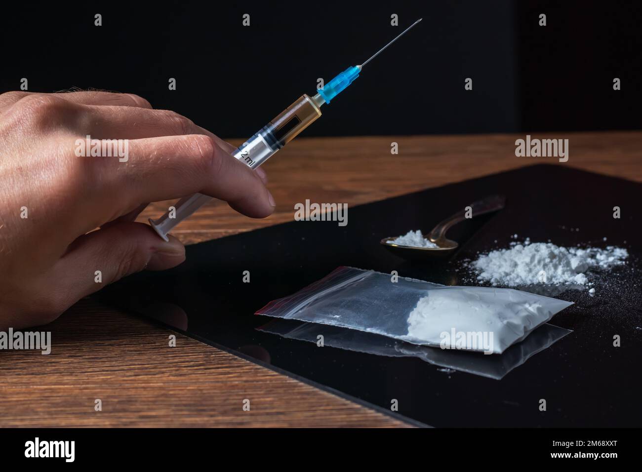 Siringa del farmaco in mano. Un tossicodipendente con un'altra dose del farmaco nella siringa. Guy dipendente, il concetto di anti-droga. tossicodipendente maschile. Foto Stock