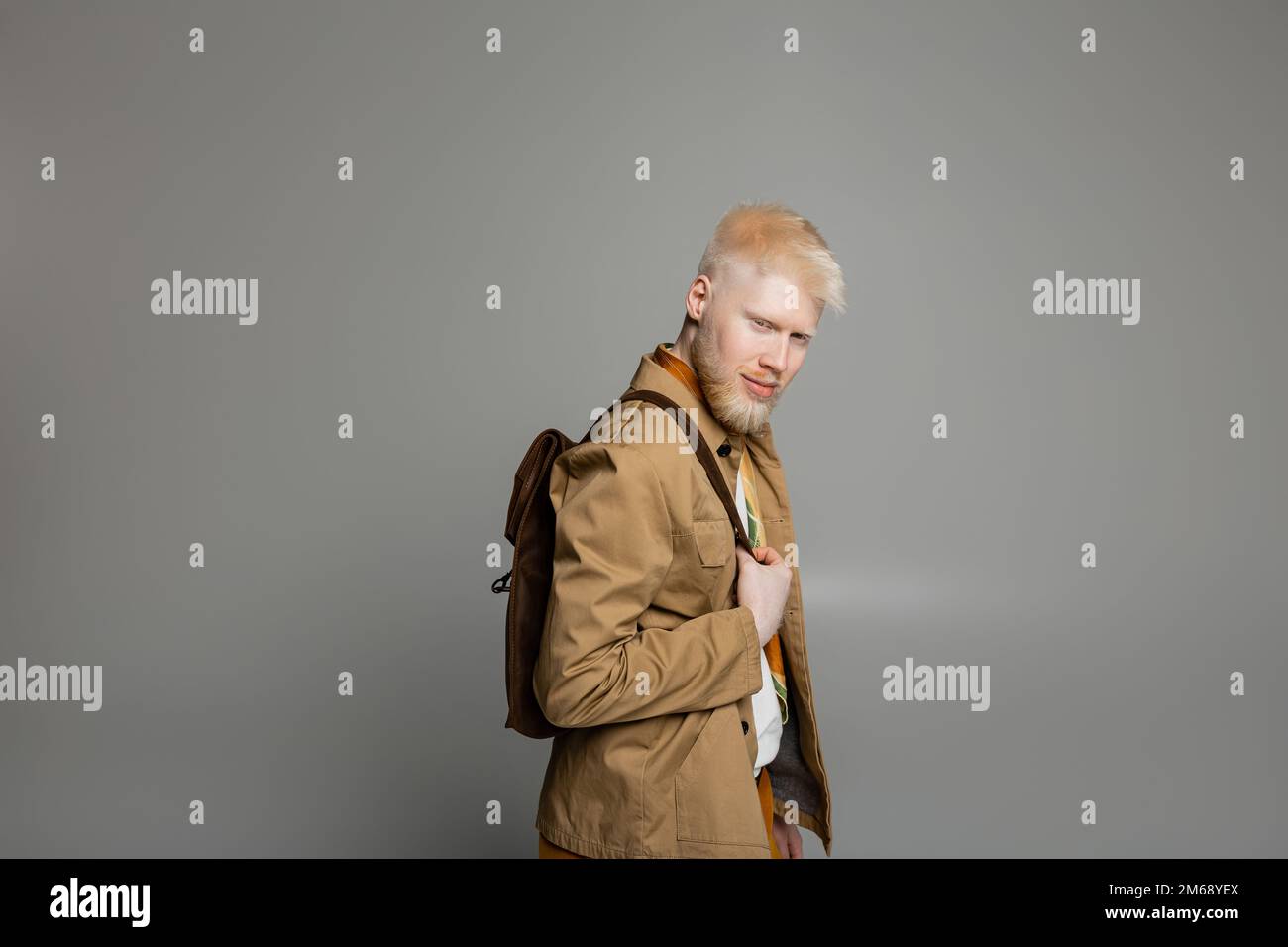 uomo albino beared in camicia elegante giacca e sciarpa di seta posa con zaino isolato su grigio, immagine stock Foto Stock