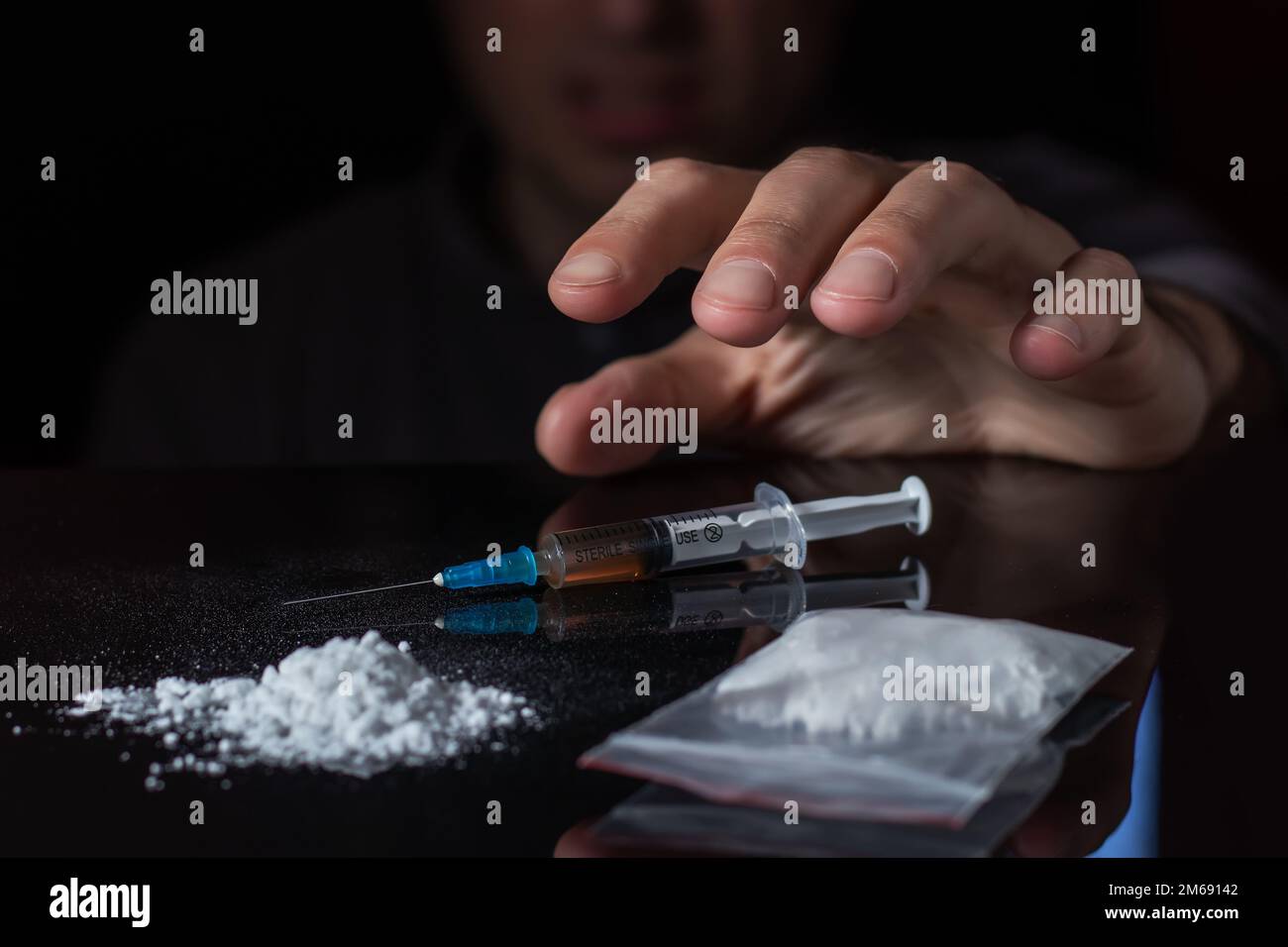 Il concetto di anti-droga. Il tossicodipendente raggiunge un'altra dose del farmaco nella siringa. Ragazzo addicted, tossicodipendente maschile, siringa di droga Foto Stock