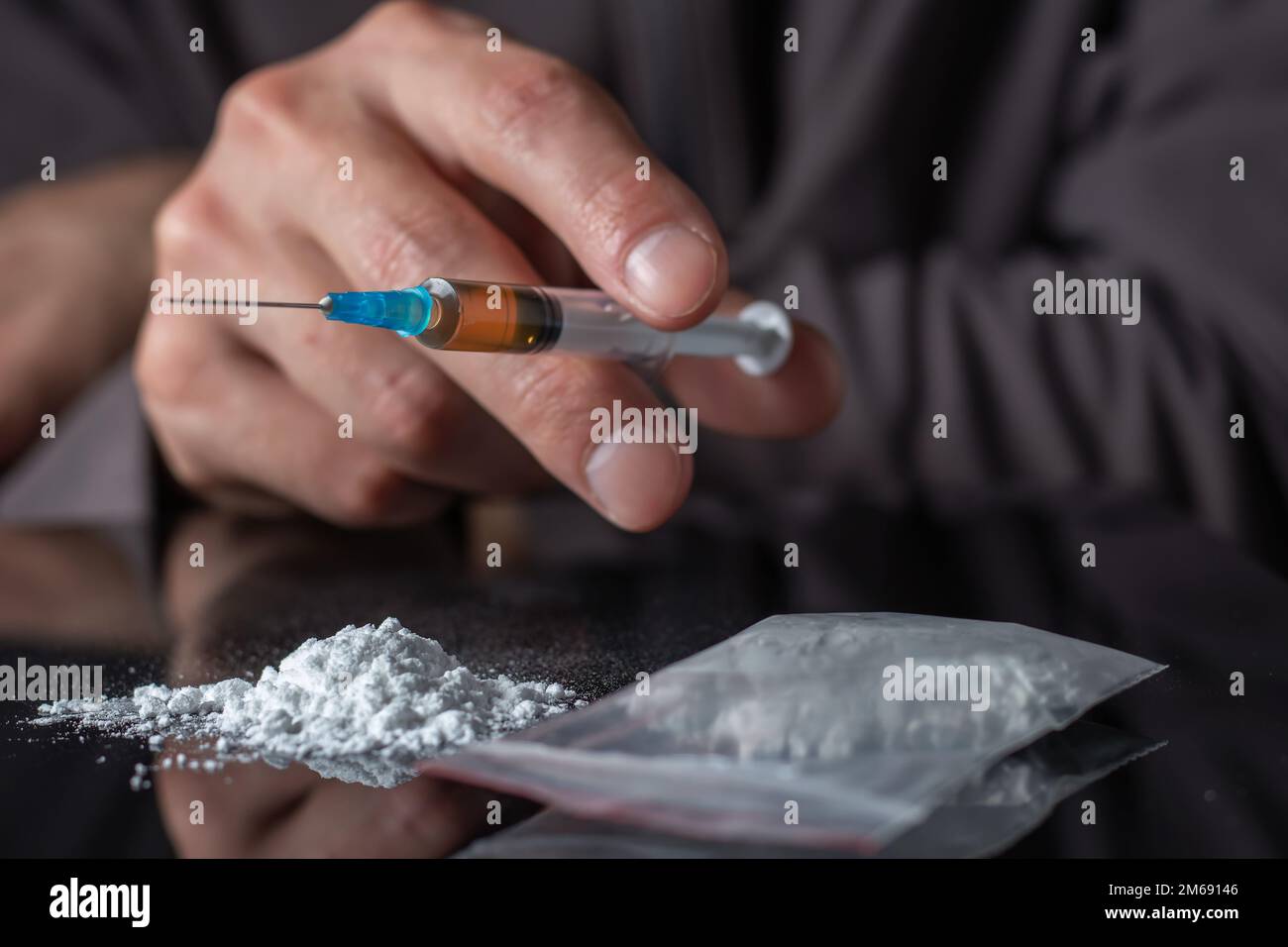 Siringa del farmaco in mano. Un tossicodipendente con un'altra dose del farmaco nella siringa. Guy dipendente, il concetto di anti-droga. tossicodipendente maschile. Foto Stock