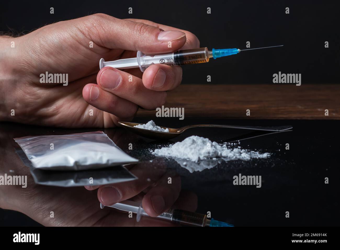 Siringa del farmaco in mano. Un tossicodipendente con un'altra dose del farmaco nella siringa. Guy dipendente, il concetto di anti-droga. tossicodipendente maschile. Foto Stock
