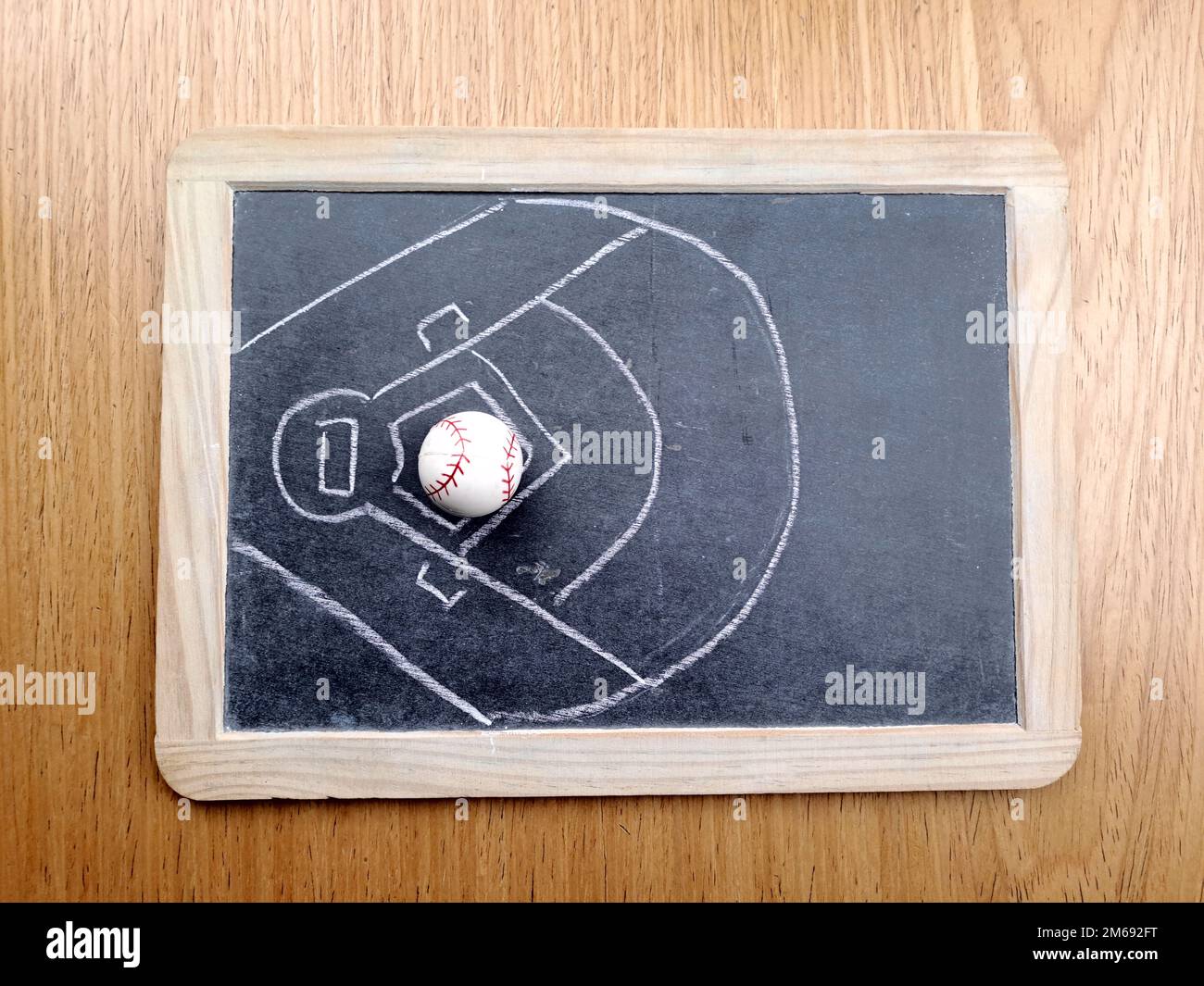 Illustrazione del campo di baseball sulla lavagna, con palla su sfondo di tavolo di legno. Foto Stock