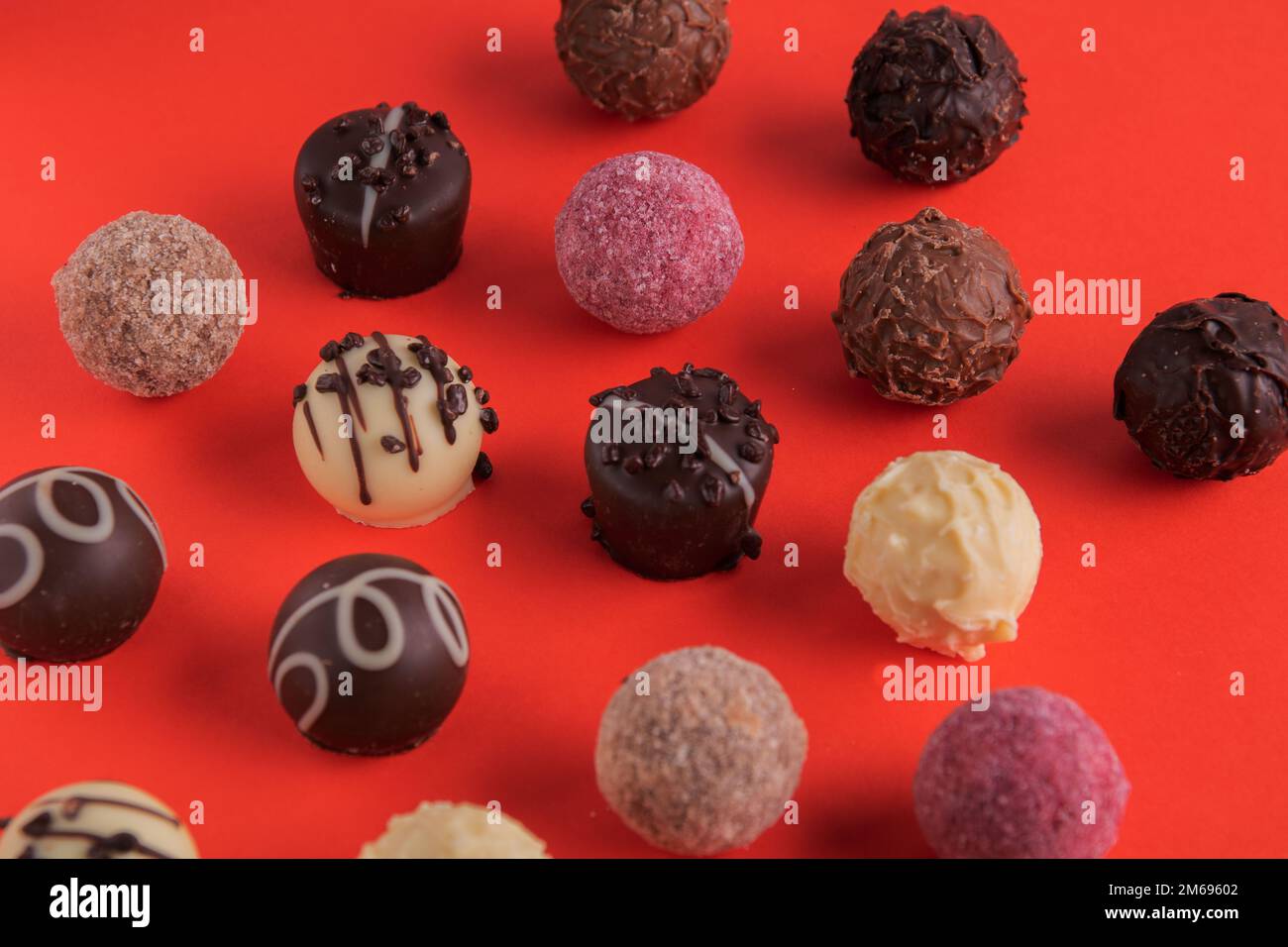 caramelle al cioccolato con decorazioni diverse su sfondo rosso Foto Stock