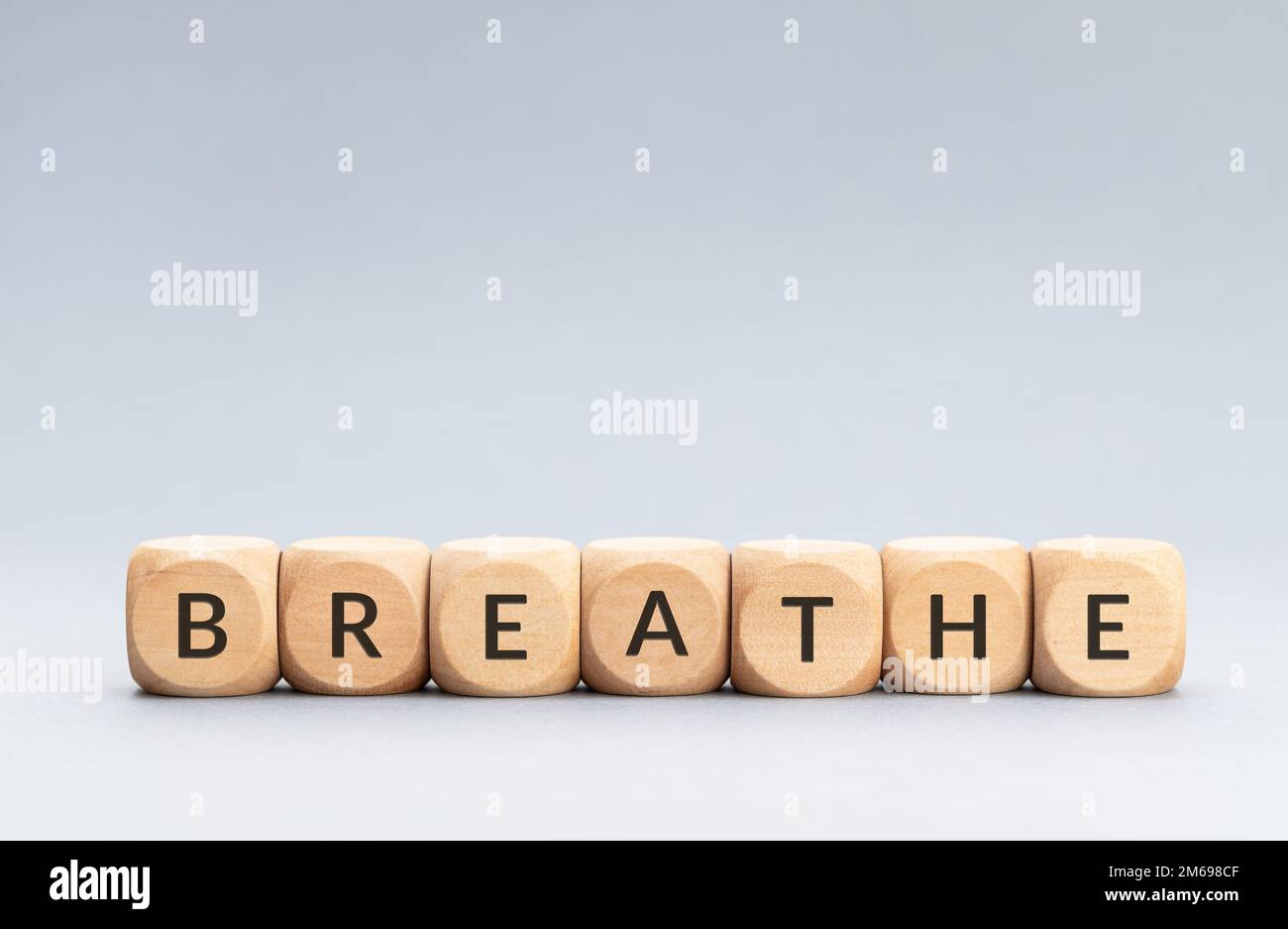 Respira la parola su blocchi di legno su sfondo grigio. Spazio di copia Foto Stock