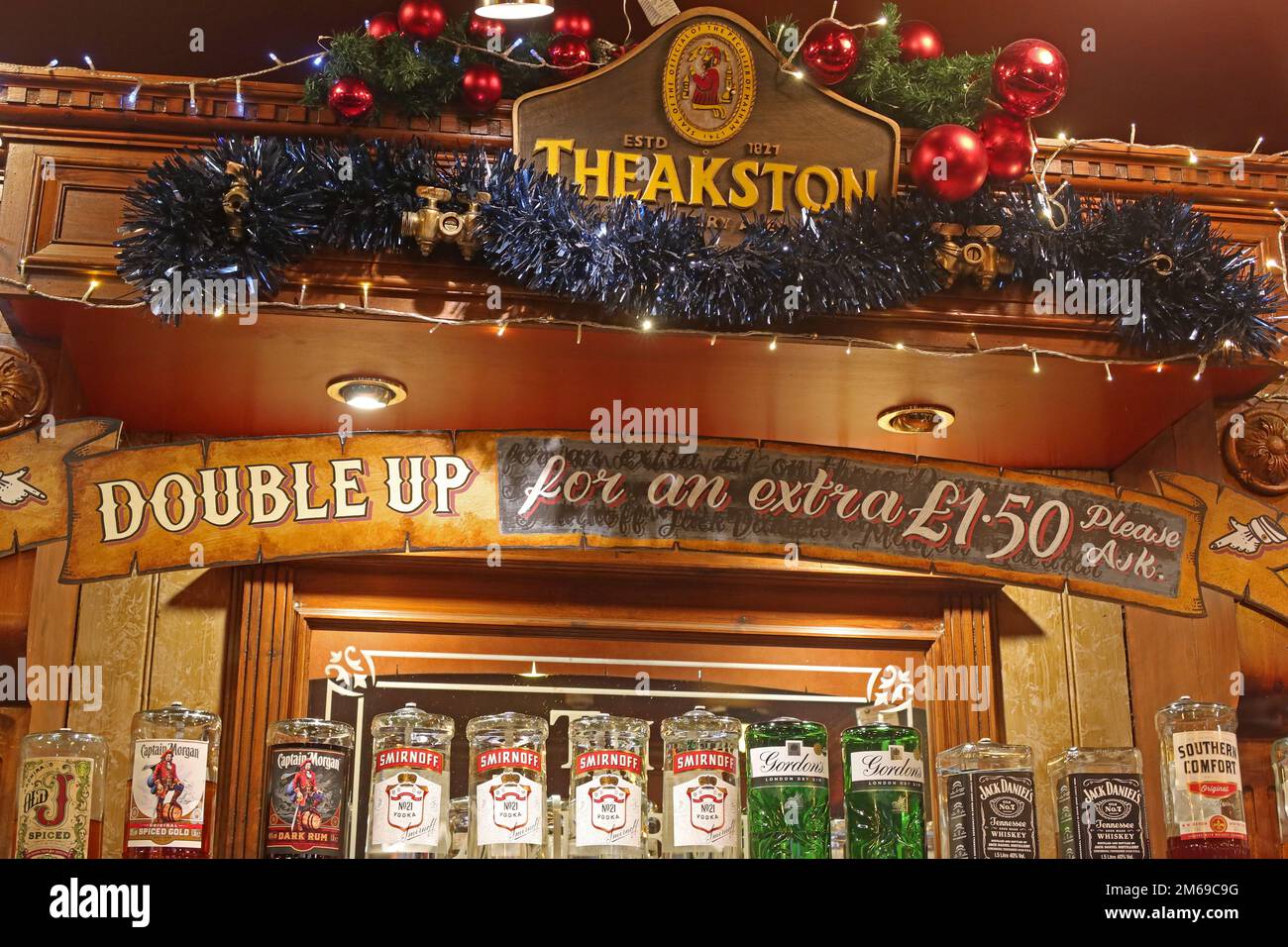 Segno che suggerisce i bevitori di Natale, dovrebbe raddoppiare gli spiriti, per appena un £1,50 supplementare, ad un pub di Theakston a Manchester, Inghilterra, Regno Unito, M1 5NE Foto Stock