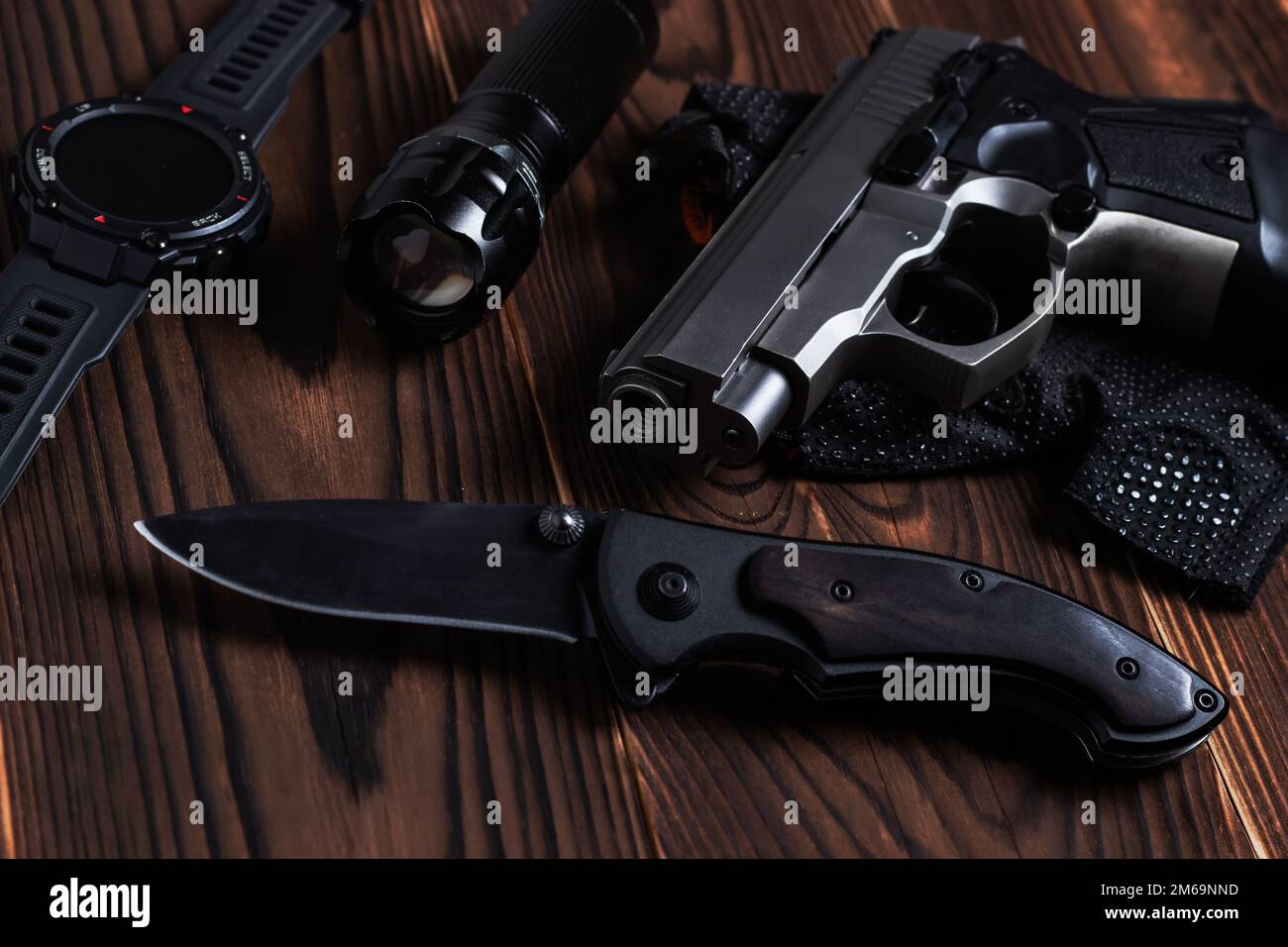 Coltello tascabile pieghevole con pistola e torcia su fondo in legno, Foto Stock