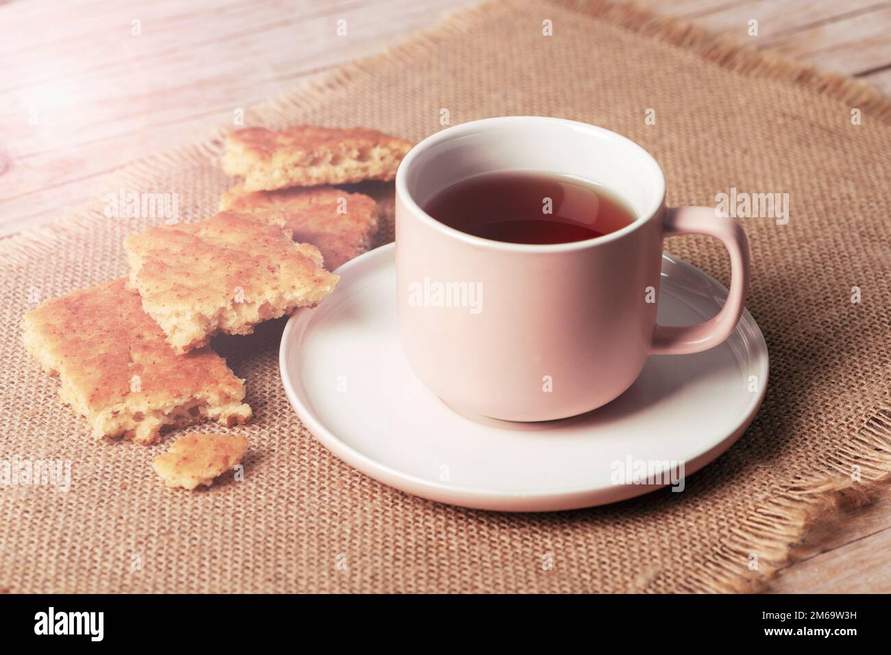 Una tazza di tè e biscotti fatti in casa su un tovagliolo di sackcloth su un tavolo di legno, primo piano. Foto Stock