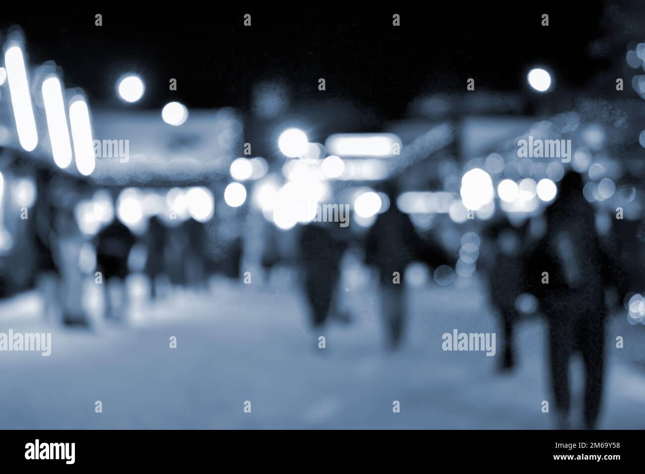 Sfondo sfocato. La gente cammina nella piazza della città la sera d'inverno. Silhouette nere di persone che camminano vicino a case decorate illuminazione luminosa. Luce bianca spot bokeh luci di casa incandescente colore blu Foto Stock
