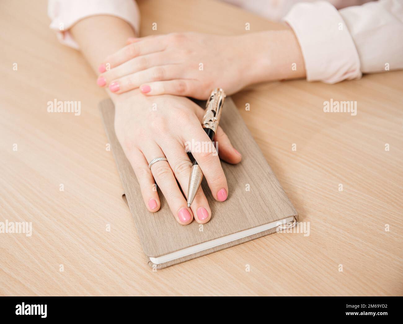 Primo piano delle mani di una donna che scrive in un notebook posto su un tavolo di legno, concetto di home Office Foto Stock