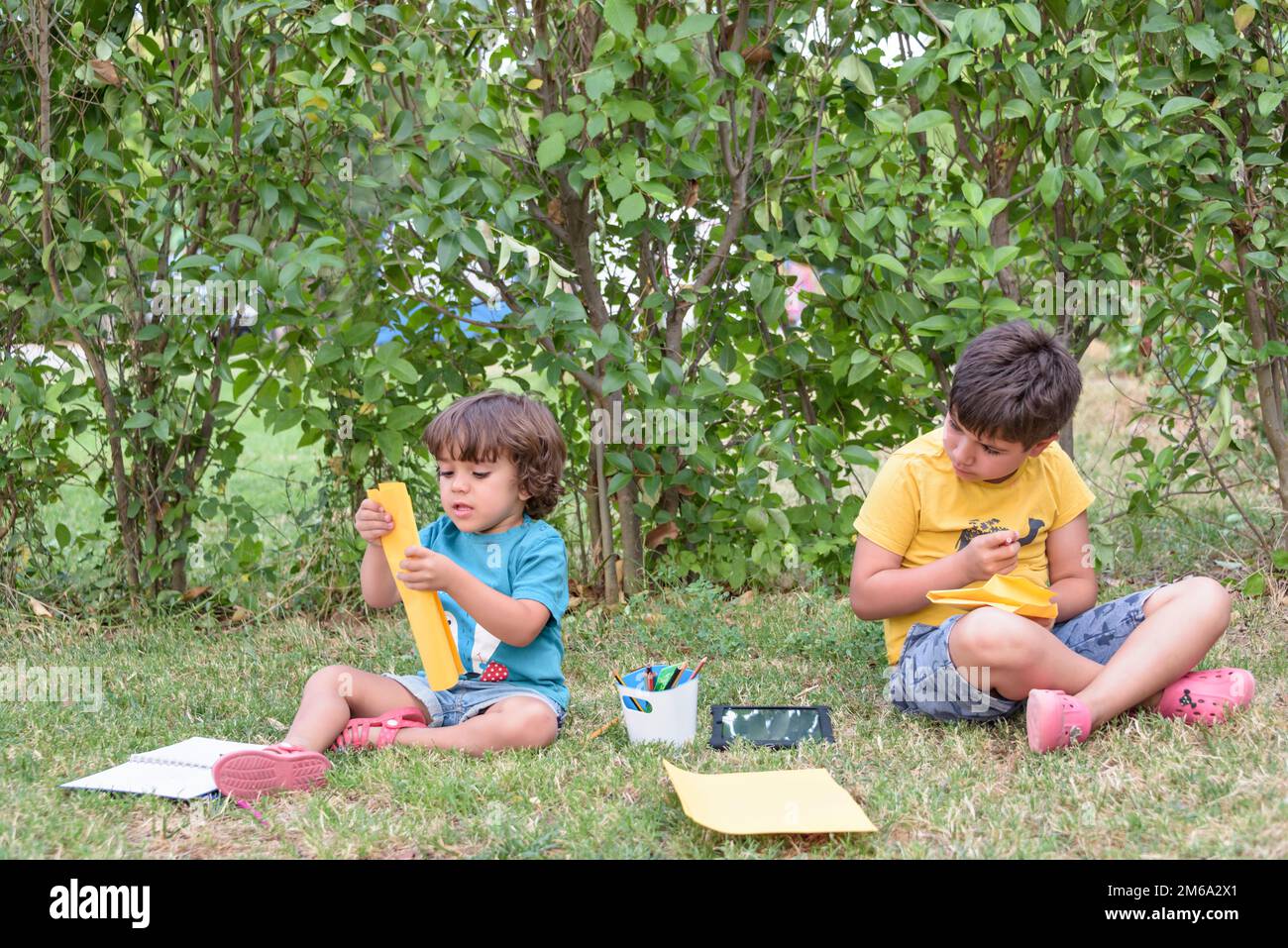 Due bambini studenti seduti a guardare il notebook nel parco. Concetto di primavera e vita di strada. Foto Stock