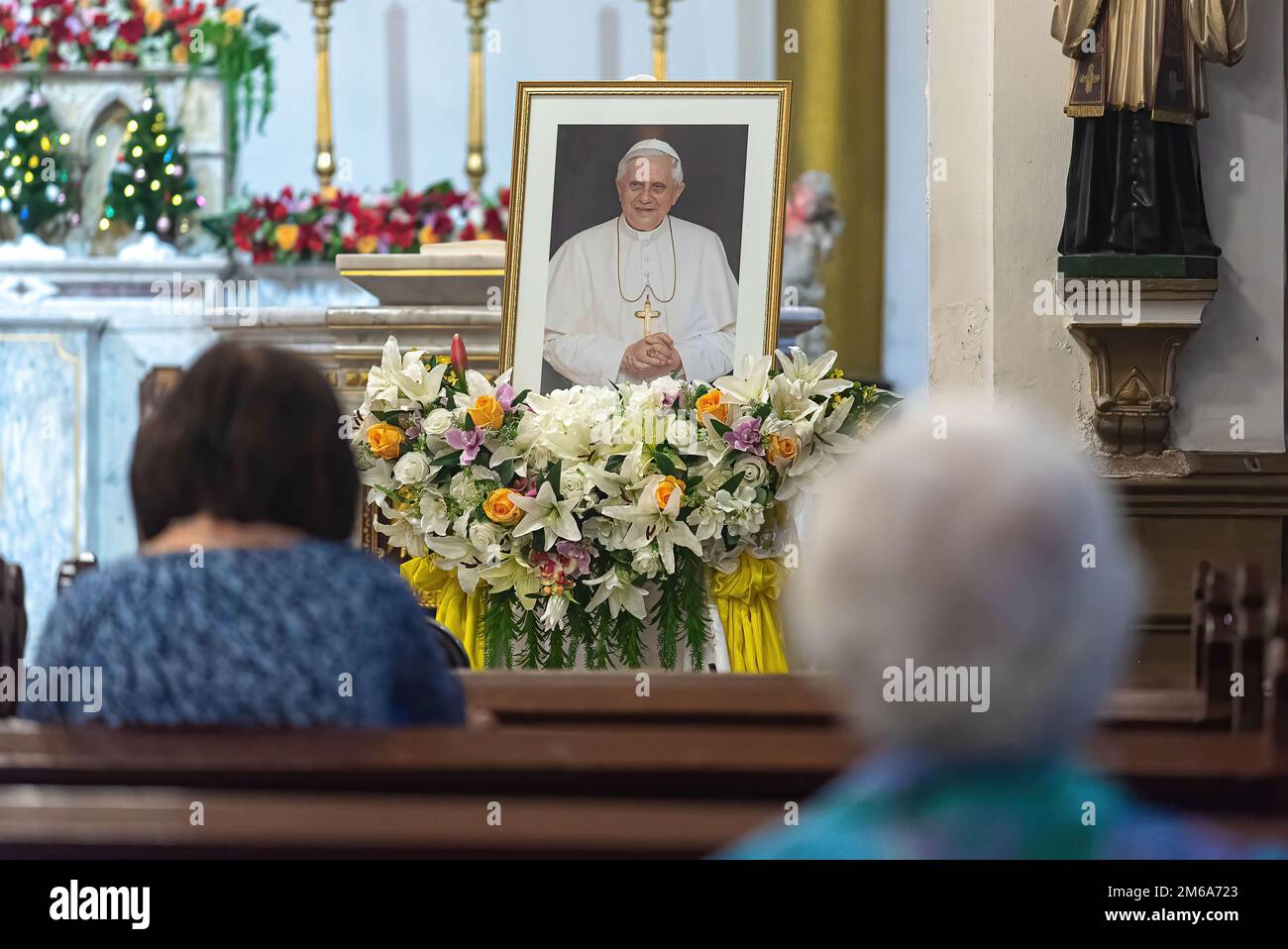 Un devoto cattolico prega davanti alla foto del compianto Papa nella Chiesa del Santo Rosario durante il tributo alla morte del Papa emerito Benedetto XVI. Il defunto Papa emerito Benedetto XVI morì il 31 dicembre 2022 all'età di 95 anni nel Monastero Mater Ecclesiae di Città del Vaticano. Foto Stock