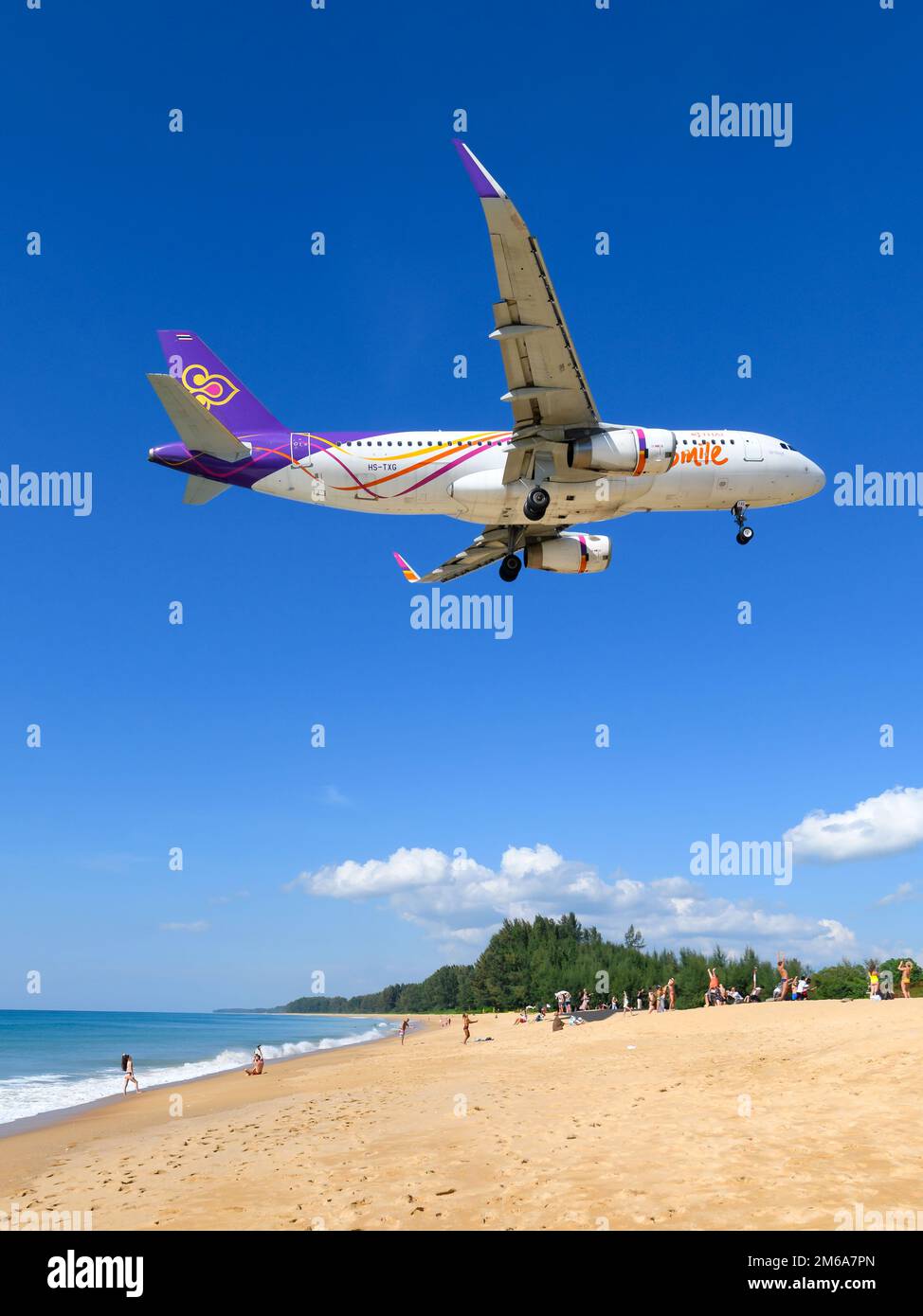 Aereo della compagnia aerea Thai Smile Airbus A320 sopra mai Khao Beach dall'Aeroporto di Phuket. Aereo A320 di Thai Smile Airways che sorvola la spiaggia turistica. Foto Stock