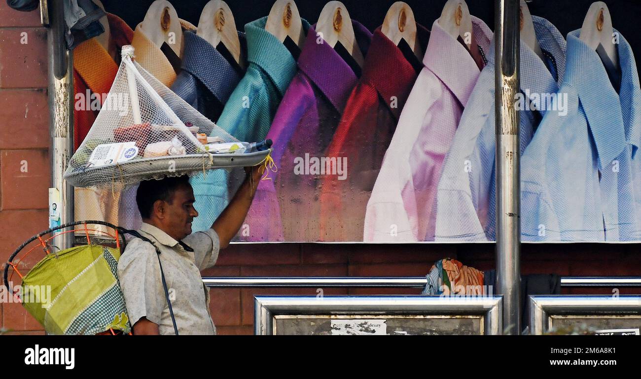 Un venditore di strada passa davanti alla pubblicità della camicia degli uomini in un rifugio per autobus. Le vendite delle aziende di abbigliamento e dei marchi lifestyle a livello globale sono salite tra il 30% e il 70% nell'anno finanziario (FY) 2022, modificando il margine di profitto rispetto a un anno in cui il 19 ha dovuto affrontare restrizioni indotte che hanno causato una contrazione delle attività e delle vendite aziendali. Foto Stock