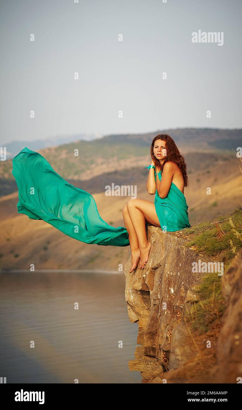 Ragazza seduta sul bordo di una scogliera Foto Stock