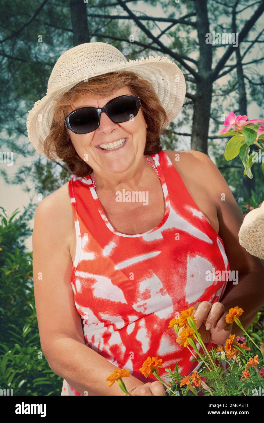 Sorridente Donna matura Pruning Fiori Foto Stock