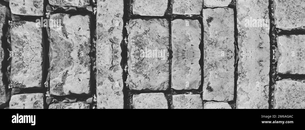 Muratura in mattoni vintage, mattoni e pietre spaccati, con una superficie intatta. Muro di pietra arrugginita. Banner Web simmetrico. Monocromatico. Copia spazio Foto Stock
