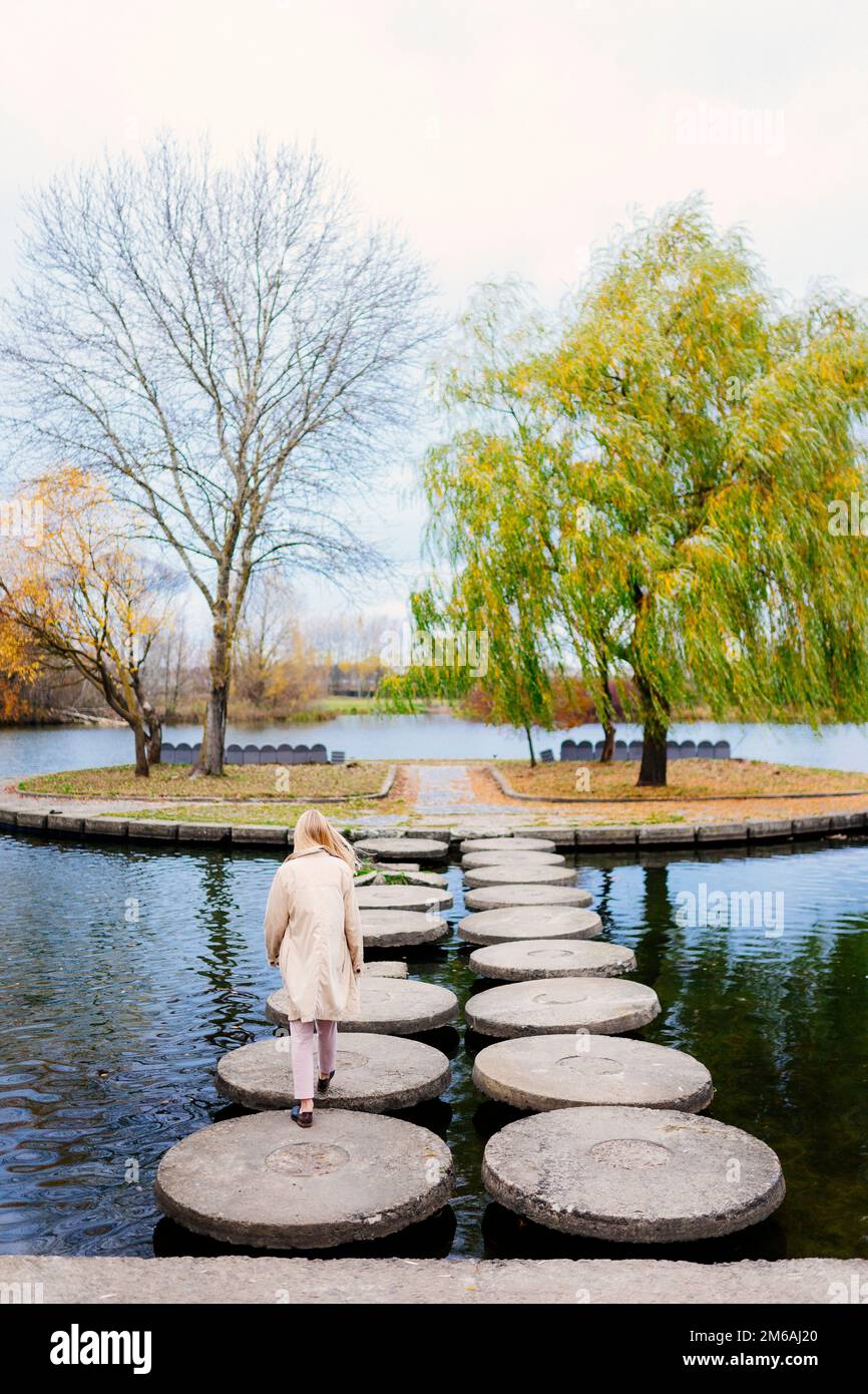 giovane donna in un cappotto che cammina vicino all'acqua Foto Stock