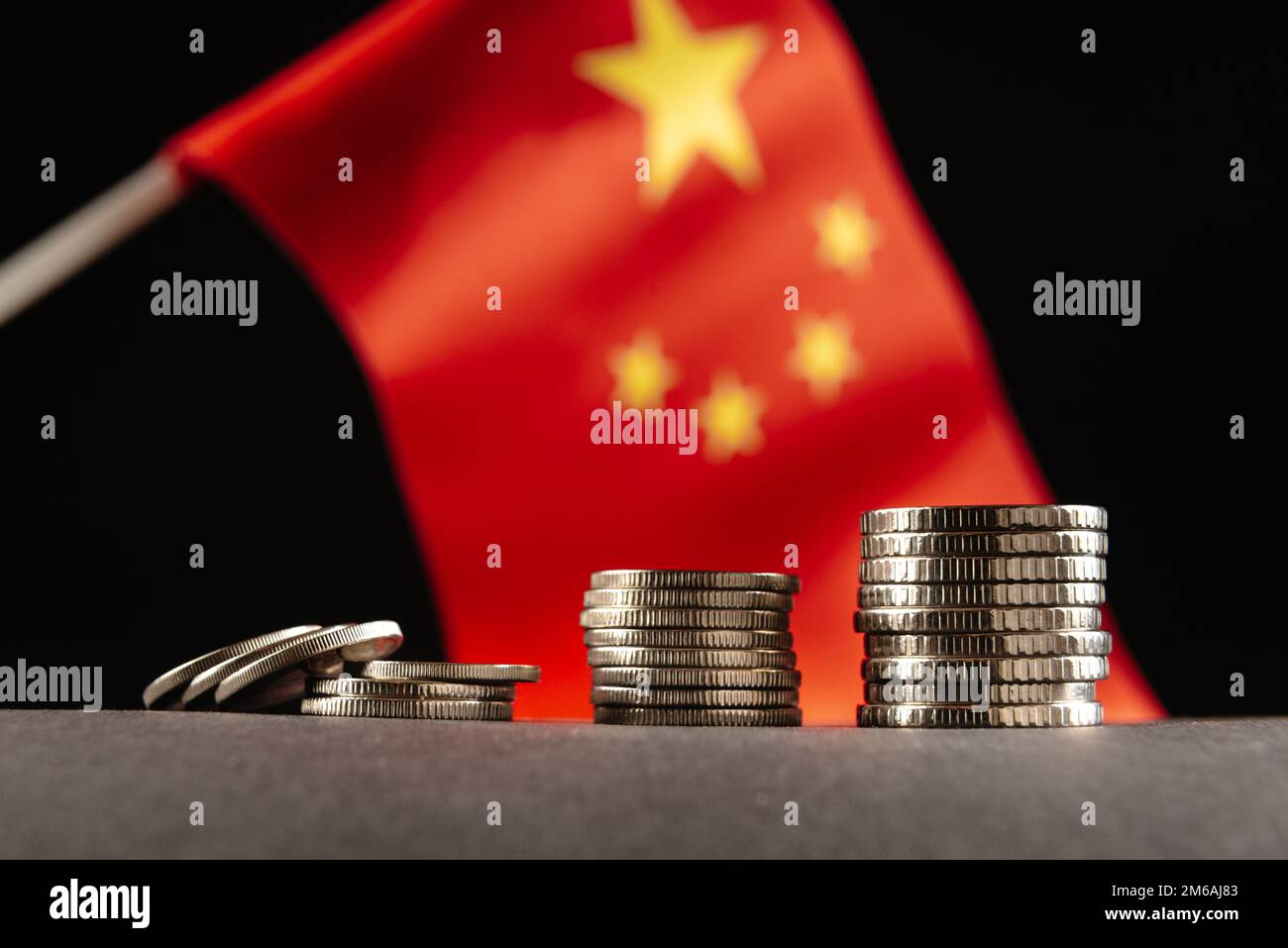 Monete cinesi con la bandiera della Repubblica popolare cinese sullo sfondo. Il concetto di crisi in Cina. Primo piano Foto Stock