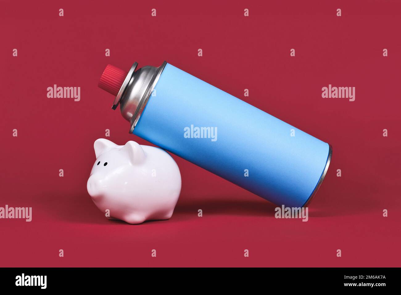Flacone a cartuccia di gas con banco di piggy su sfondo rosso. Concetto per il risparmio di gas. Foto Stock