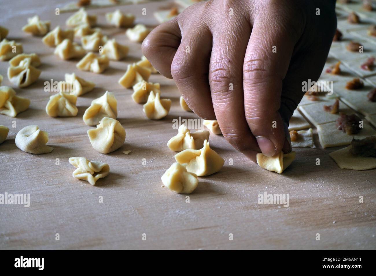 Preparare il tradizionale cibo turco Mantı. Ravioli Turchi crudi fatti a mano (manti). Gnocchi fatti in casa di cucina turca. Foto Stock