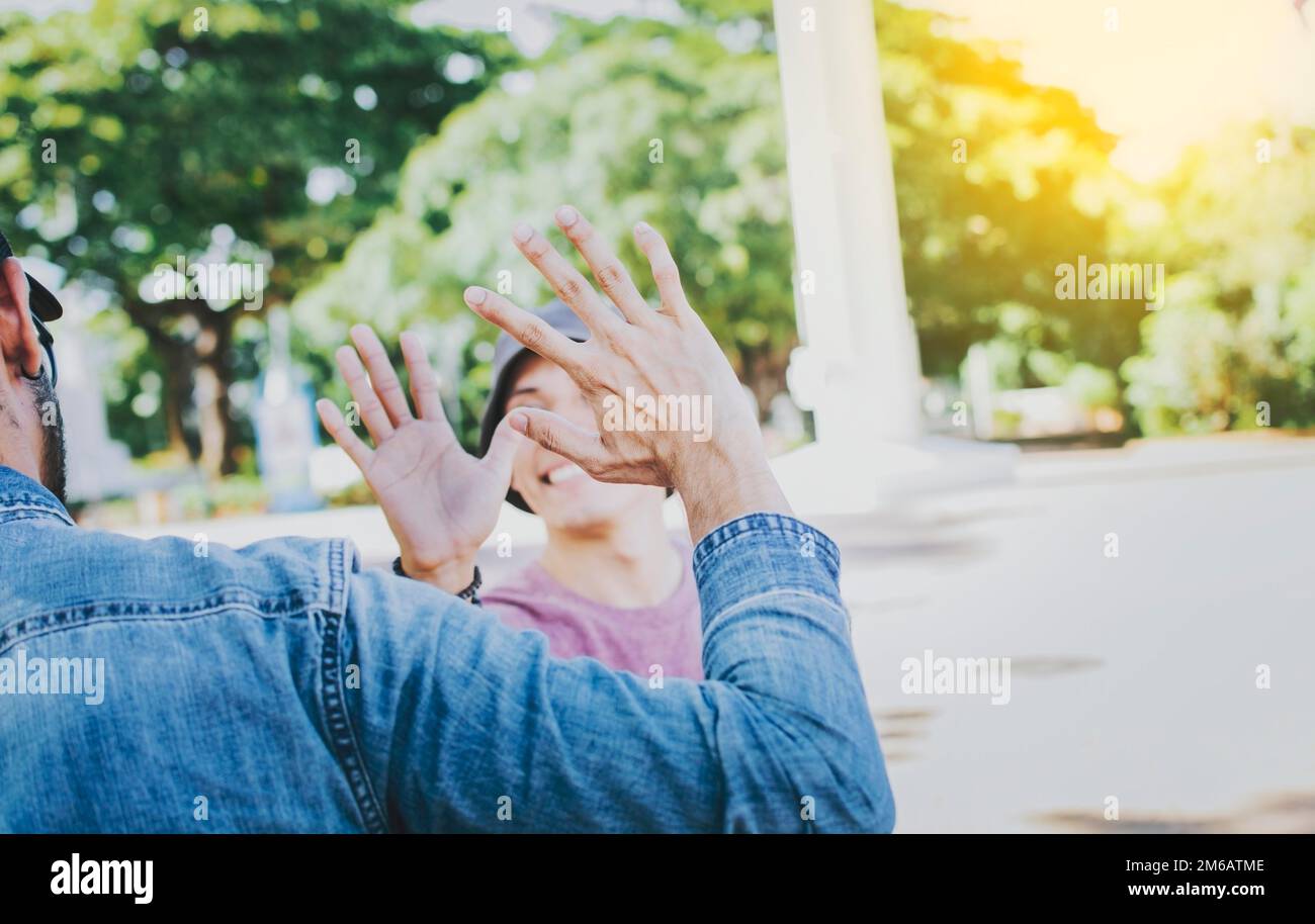 Primo piano di gente sorridente che scuote le mani in un parco. Concetto di due amici che si salutano con una stretta di mano sulla strada, Vista posteriore di due Foto Stock