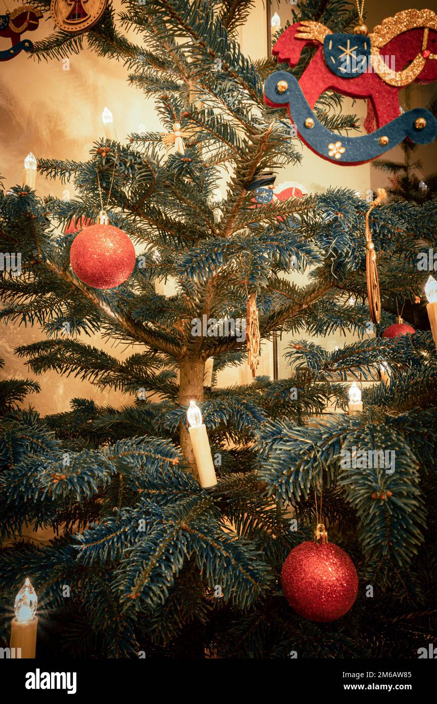 Palline rosse di Natale su un albero di Natale e un cavallo a dondolo fatto di feltro con le luci dell'albero di Natale, Hannover, bassa Sassonia, Germania Foto Stock