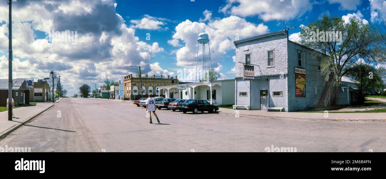 Un giovane adulto con rollerblade pattinaggio nel mezzo di Main Street senza traffico a Edmore, North Dakota - 28 maggio 1995 Foto Stock