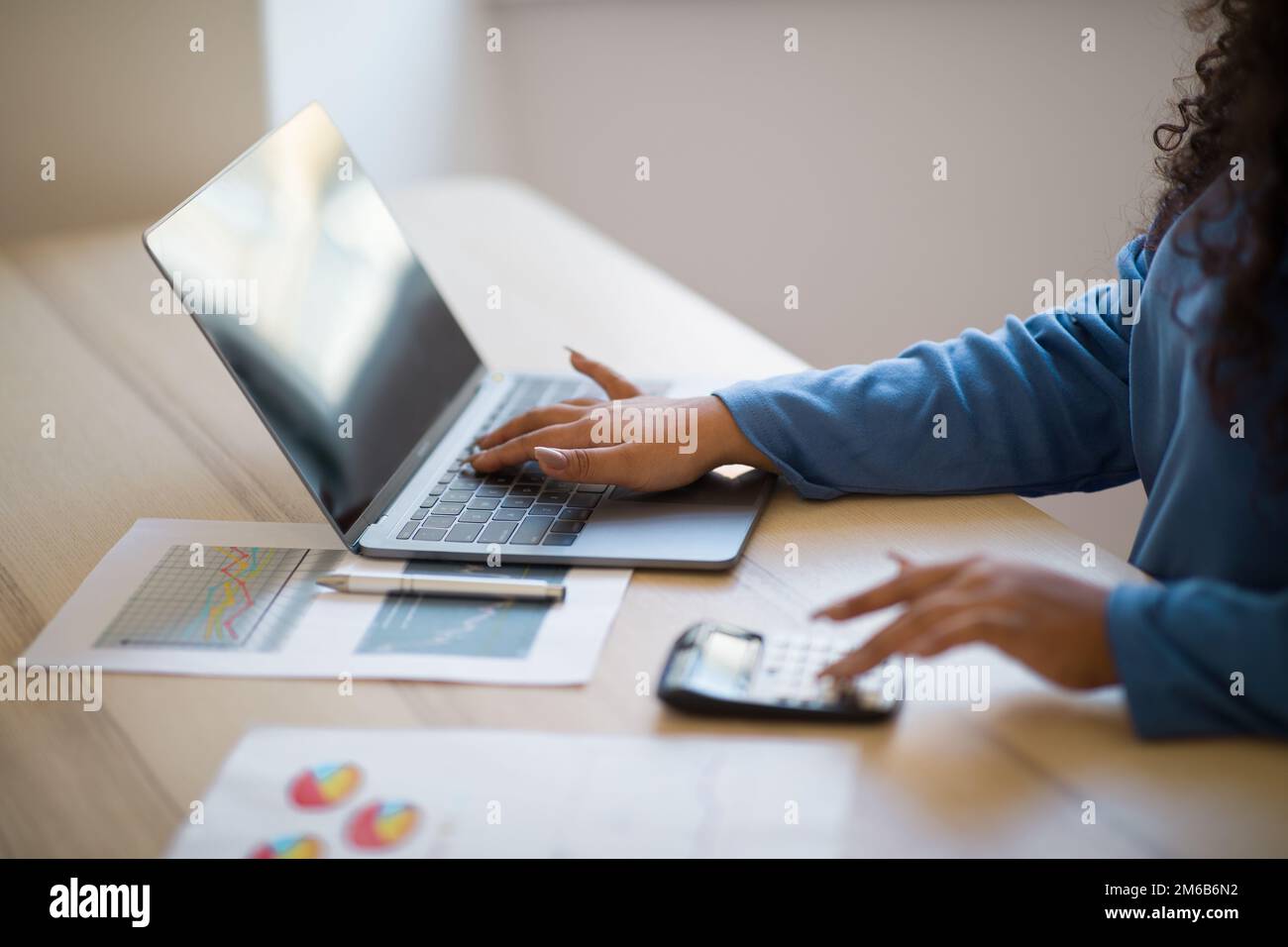 Primo piano focalizzazione sulle mani femminili che eseguono calcoli sul computer portatile Foto Stock
