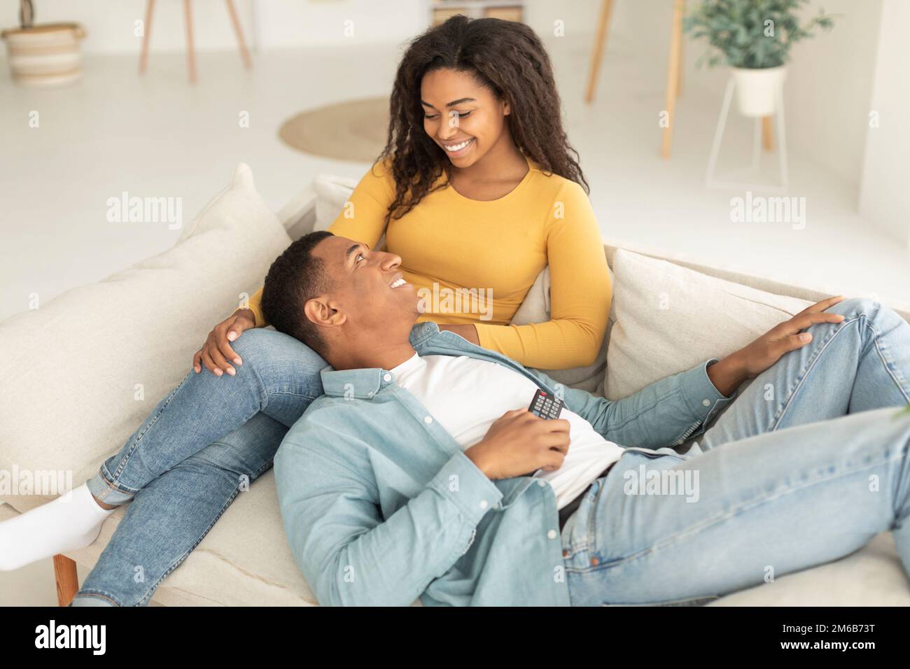 Allegra coppia afro-americana millenaria con telecomando goditi il tempo libero e i momenti teneri, rilassati Foto Stock