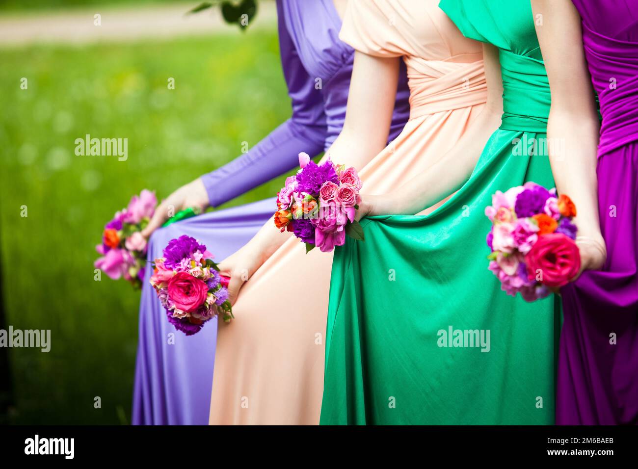 Bridesmaids in abiti colorati con bouquet di f Foto Stock