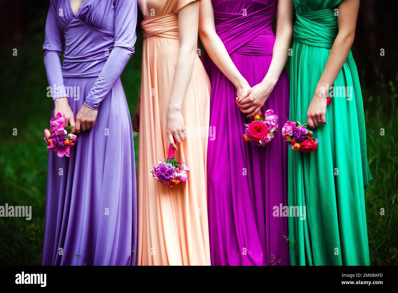 Bridesmaids in abiti colorati con bouquet di f Foto Stock